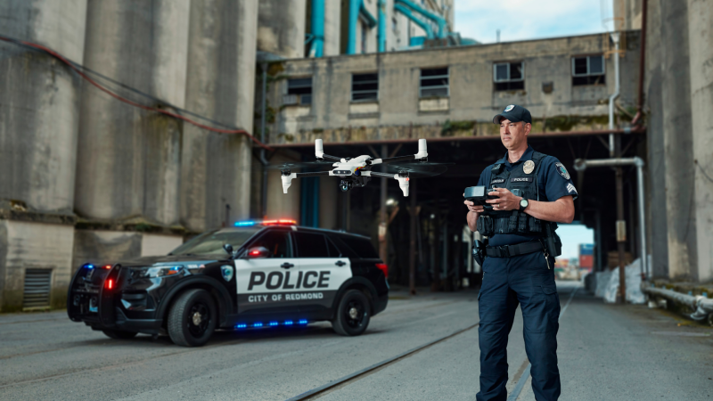 Police Officer flying BRINC drone in front of a police car